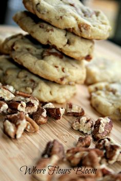 a pile of cookies sitting on top of a wooden cutting board next to pecans