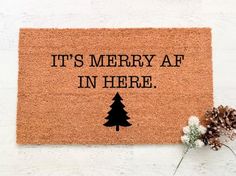 a door mat that says it's merry af in here with a pine tree