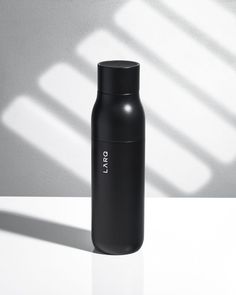 a black bottle sitting on top of a white table