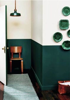 a room with green walls and plates on the wall, along with a chair in the corner