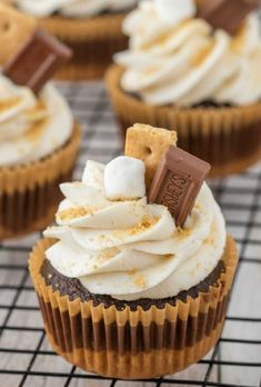 chocolate cupcakes with white frosting and marshmallows are on a cooling rack