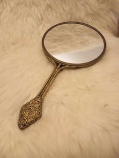 an antique looking magnifying glass sitting on top of a white fur covered floor