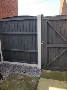 a dog is standing in front of a gate that has been built into the side of a building