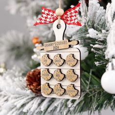 a christmas ornament with cookies on it hanging from a tree in front of snow covered branches