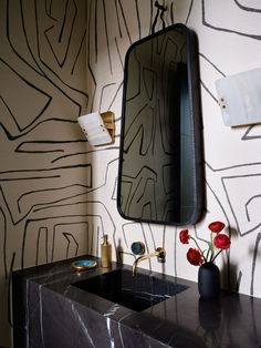 a bathroom sink with a black marble counter top and wall paper on the wall behind it