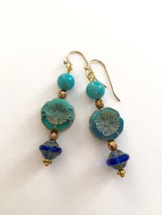 "Lightweight earrings handmade of semi-transparent aqua blue Czech glass Picasso flower, 8mm turquoise howlite, and cobalt blue Picasso UFO bead. Accented with light bronze Czech glass beads and gold wire. Earrings come on simple gold plated fish hook ear wires, lead and nickel free. Measure 2 1/8\"'long from top of ear wire." Artisan Blue Beaded Round Earrings, Artisan Blue Beaded Earrings, Blue Round Beaded Earrings With Spacer Beads, Handmade Blue Round Bead Earrings, Blue Flower Earrings Nickel Free, Blue Flower Earrings For Jewelry Making, Blue Flower-shaped Jewelry For The Beach, Blue Flower Jewelry For The Beach, Turquoise Czech Glass Beaded Earrings