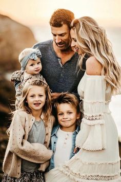 a man standing next to two women and two children on top of a rocky beach