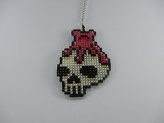 a cross stitch skull ornament hanging on a string