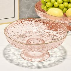 two bowls filled with fruit sitting on top of a table next to a framed photo