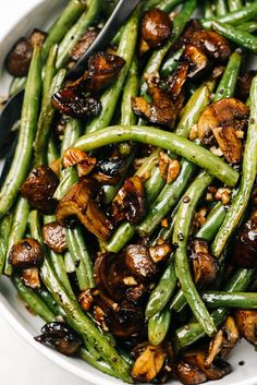 green beans and mushrooms in a white bowl with a serving utensil on the side