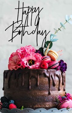 a birthday cake with chocolate frosting and fresh flowers on top that says happy birthday