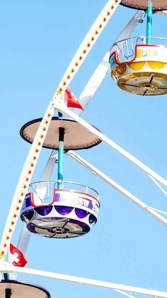 the ferris wheel is brightly colored and has four seats on each side, as well as several other rides