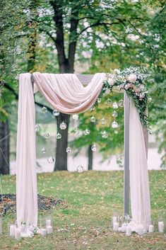 an outdoor wedding ceremony set up with white flowers, candles and draping on the ground