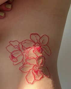 a woman's stomach with red thread on it and flowers drawn on the side