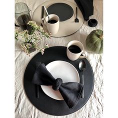 a place setting with black napkins and white plates