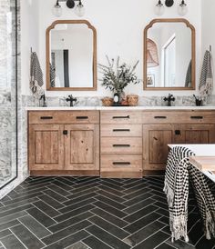 a bathroom with two mirrors and double sinks in it's center, surrounded by marble tiles