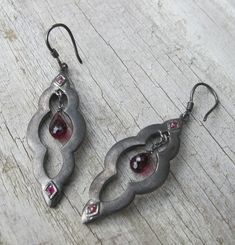 A unique bohemian pair of Moroccan-inspired dangle earrings handcrafted in oxidized sterling silver accented with a garnet and ruby. A stunning and one-of-a-kind earring that make a great birthstone earrings for the month of January(Garnet) and Ruby(July) (E.96) *Follow us @belesasjewelry on Instagram for promotions/giveaways *LIKE* us on Facebook http://www.facebook.com/Belesas  *If you like the ring, please click on the "Pin It" icon ---------------------------------------------------- ENTER M Antique Silver Jewelry Vintage, Black Earrings Dangle, Earrings Stone, Earrings Gemstone, Birthstone Earrings, Nail Jewelry, Dope Jewelry, Statement Earring, Garnet Earrings