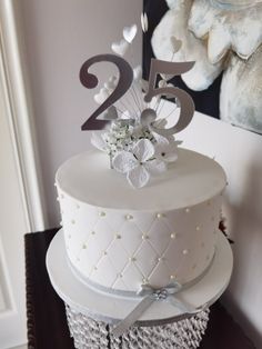 a white wedding cake with silver numbers and flowers