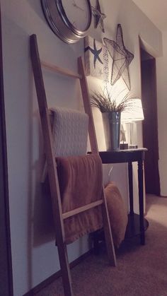 a ladder leaning up against a wall next to a table with a lamp on it