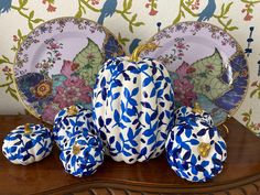 blue and white pumpkins sitting on top of a wooden table next to two plates