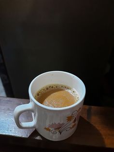 a cup of coffee sitting on top of a wooden table