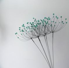 a vase filled with lots of green flowers on top of a wooden table next to a white wall