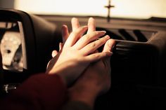 two hands on the steering wheel of a car, with a cross in the background