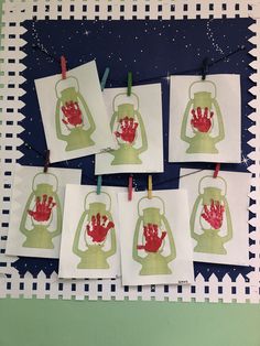 four cards with red hand prints hanging from clothes pins on a blue and green background