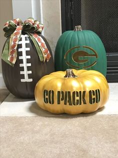 three painted pumpkins sitting next to each other on the floor in front of a fireplace