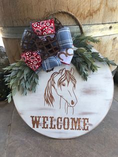 a welcome sign with a horse on it and bows hanging from the front of it