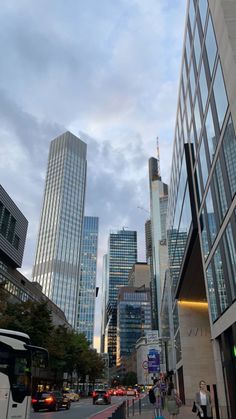 a city street with tall buildings and people walking on the sidewalk in front of it