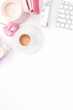 a cup of coffee next to a keyboard and mouse on a white desk with pink flowers