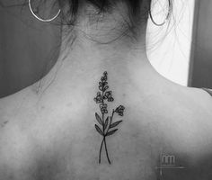 the back of a woman's neck with a flower tattoo on it