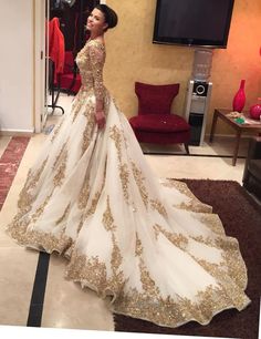 a woman in a white and gold wedding dress standing in front of a television screen