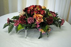 a bouquet of flowers sitting on top of a white tablecloth covered round table cloth