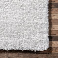 a white rug on top of a wooden floor next to a wood planked wall