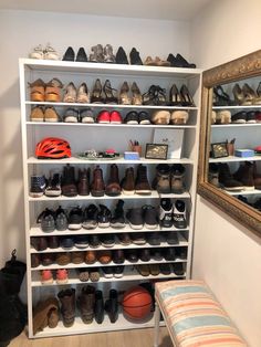 a shoe rack filled with lots of shoes next to a mirror