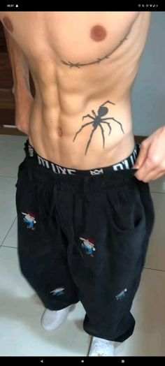 a man with a spider tattoo on his stomach is standing in front of the camera