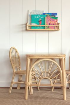 two chairs and a table with books on the shelf above them in a white room