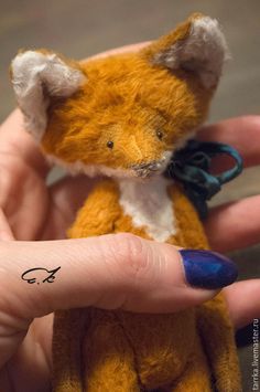 a small stuffed animal in someone's hand with a tiny tattoo on the finger