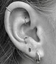 a close up of a person's ear with three piercings