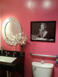 a bathroom with pink walls and a white toilet next to a black counter top sink