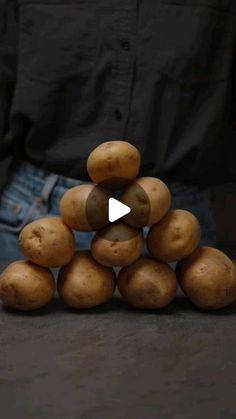 a pile of potatoes sitting on top of each other in front of a man's jeans