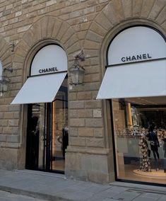 two chanel storefronts with white awnings on the side of a building