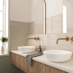 two white bowls sitting on top of a counter next to each other in a bathroom