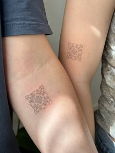 two people with matching tattoos on their arms, one is holding the other's arm