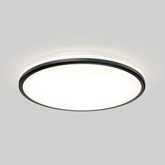 a white ceiling light with black trim on a gray wall behind it is an oval shape