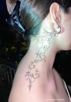 the back of a woman's neck with an intricate tattoo design on her left side