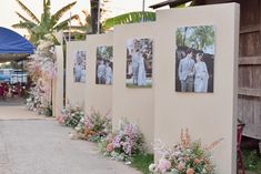 several pictures are hanging on the side of a wall with flowers in front of them