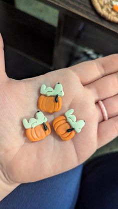 three little pumpkins are sitting on someone's hand, one is green and the other is orange